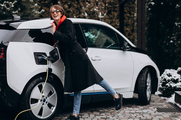 Mujer cargando electro car por su casa