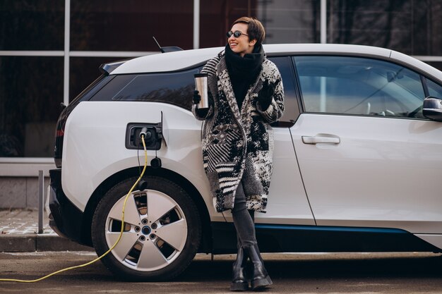 Mujer cargando electro coche en la calle