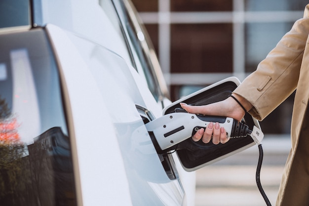 Mujer cargando electro coche en la gasolinera eléctrica