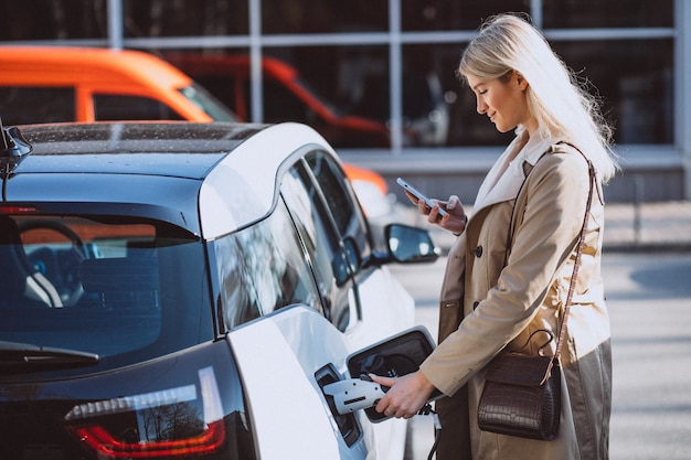 Mujer cargando electro coche en la gasolinera eléctrica