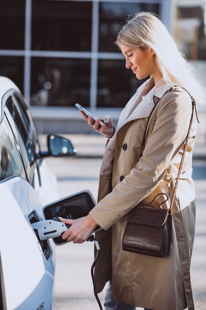 Mujer cargando electro coche en la gasolinera eléctrica