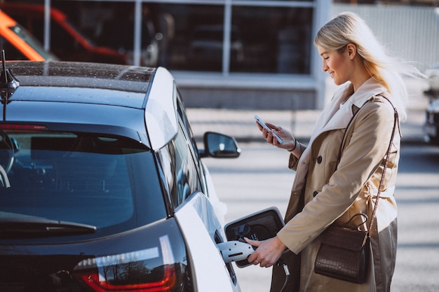 Mujer cargando electro coche en la gasolinera eléctrica