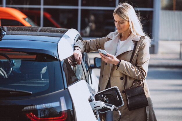 Mujer cargando electro coche en la gasolinera eléctrica