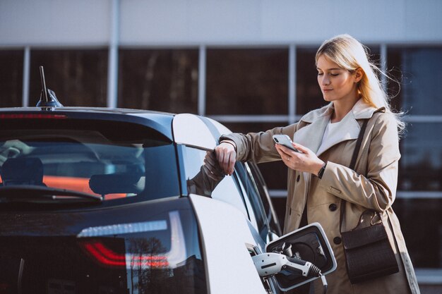 Mujer cargando electro coche en la gasolinera eléctrica