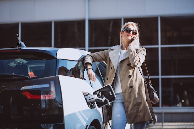 Mujer cargando electro coche en la gasolinera eléctrica