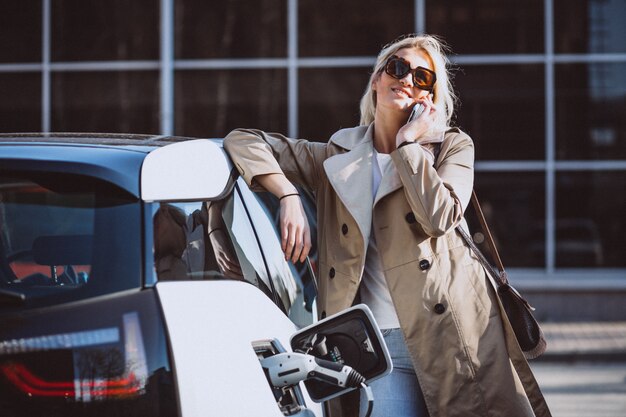 Mujer cargando electro coche en la gasolinera eléctrica