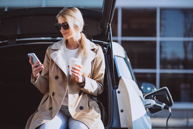 Mujer cargando electro coche en la gasolinera eléctrica