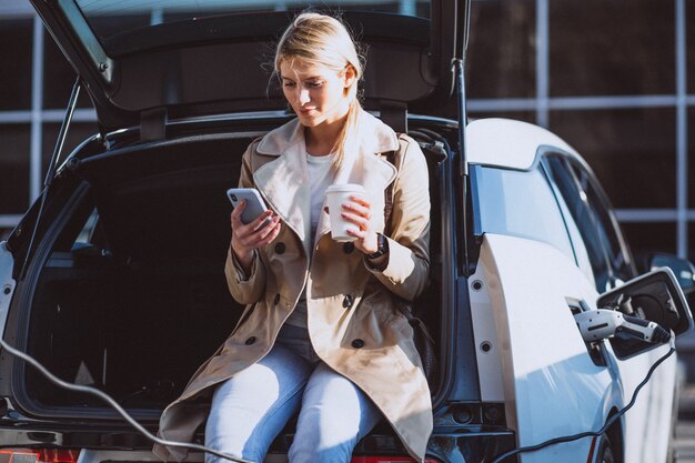 Mujer cargando electro coche en la gasolinera eléctrica