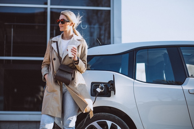 Mujer cargando electro coche en la gasolinera eléctrica