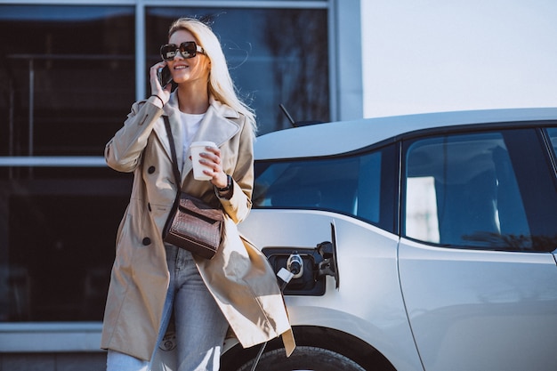 Mujer cargando electro coche en la gasolinera eléctrica