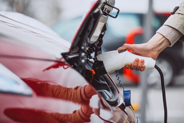 Mujer cargando electro coche en la gasolinera eléctrica