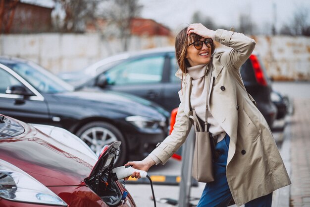 Mujer cargando electro coche en la gasolinera eléctrica