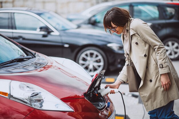 Mujer cargando electro coche en la gasolinera eléctrica