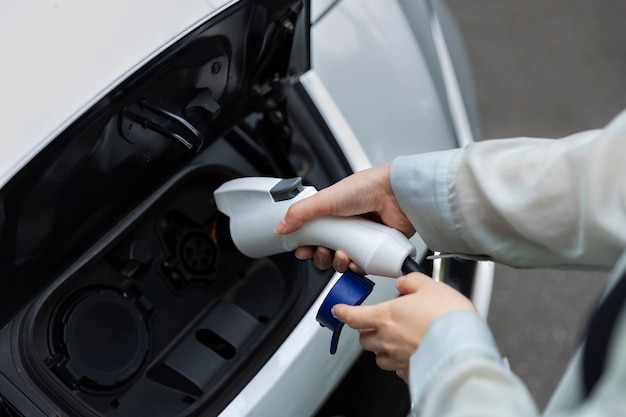 Mujer cargando su auto eléctrico en la estación