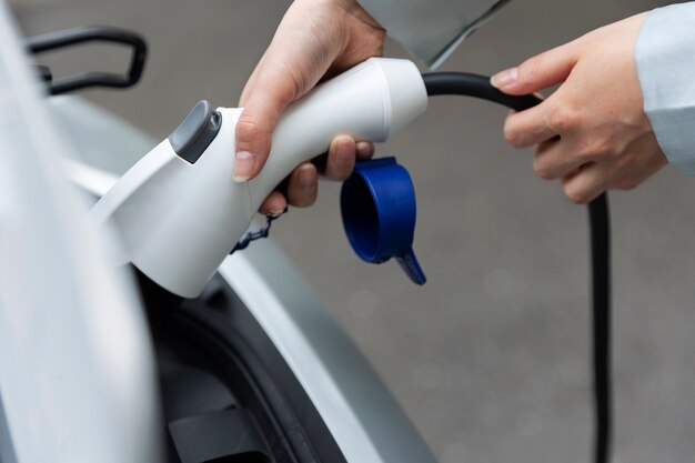 Mujer cargando su auto eléctrico en la estación