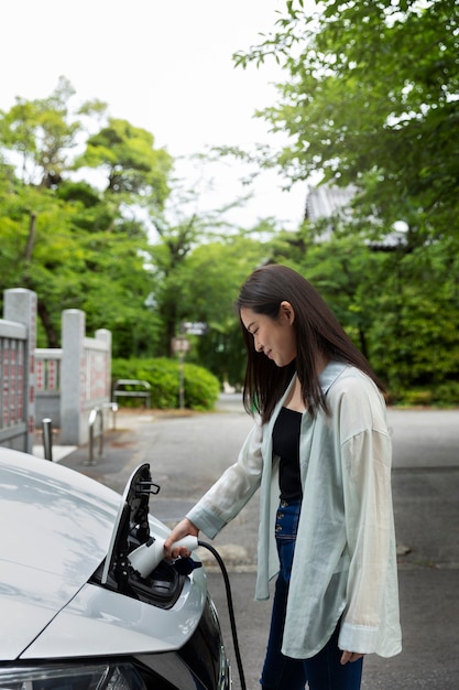 Mujer cargando su auto eléctrico en la estación