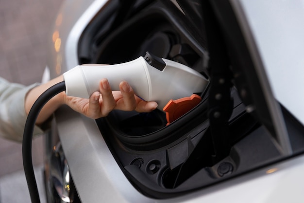 Foto gratuita mujer cargando su auto eléctrico en la estación