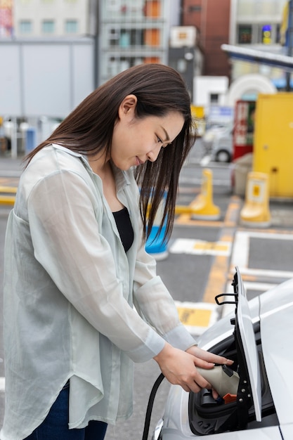 Mujer cargando su auto eléctrico en la estación