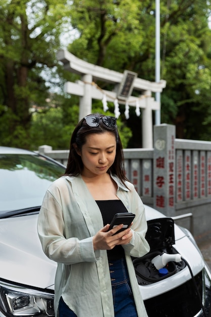 Mujer cargando su auto eléctrico en la estación