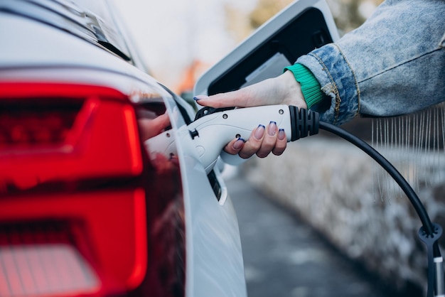 Mujer cargando su auto eléctrico con pistola de carga