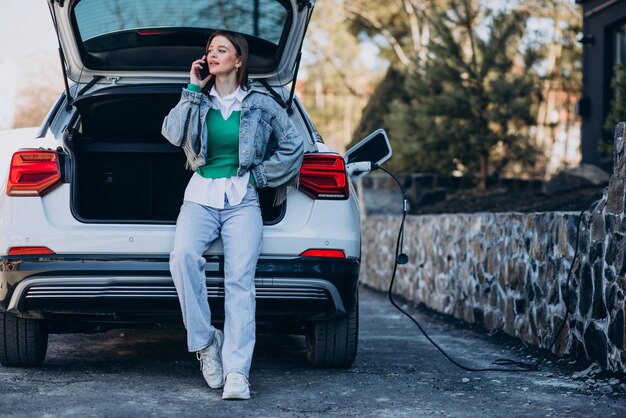 Mujer cargando su auto eléctrico con pistola de carga