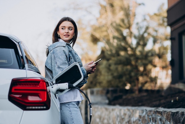 Mujer cargando su auto eléctrico con pistola de carga