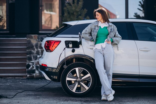 Mujer cargando su auto eléctrico con pistola de carga