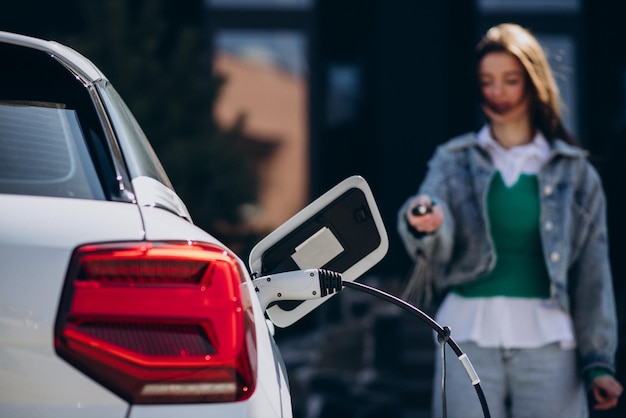 Mujer cargando su auto eléctrico con pistola de carga