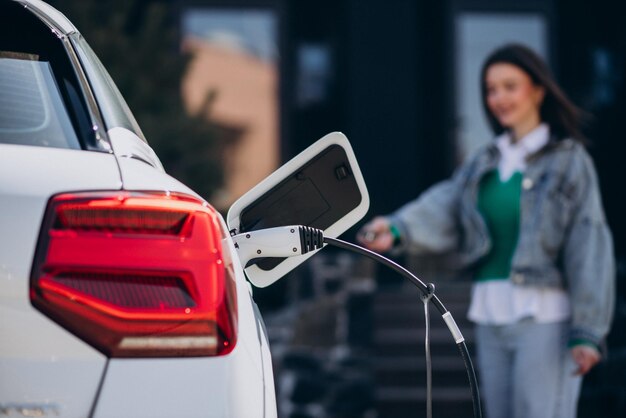 Mujer cargando su auto eléctrico con pistola de carga