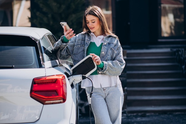 Mujer cargando su auto eléctrico con pistola de carga