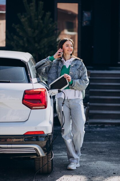 Mujer cargando su auto eléctrico con pistola de carga