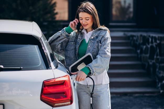 Mujer cargando su auto eléctrico con pistola de carga