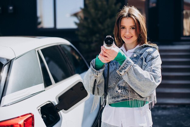 Mujer cargando su auto eléctrico con pistola de carga