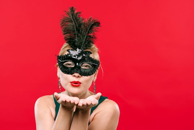 Mujer en carnaval negro máscara beso soplado