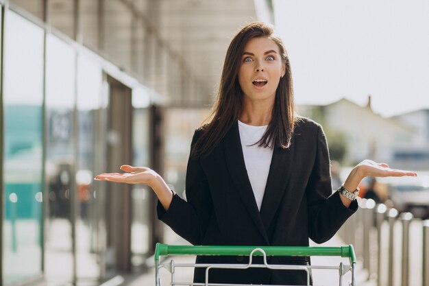 Mujer, con, carro de compras, por, tienda de comestibles