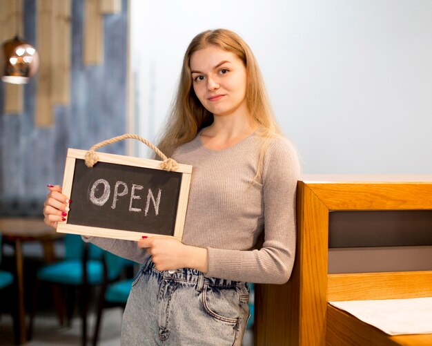 Mujer con cartel abierto para cafetería