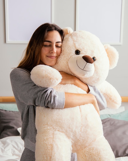 Mujer en casa abrazando gran oso de peluche