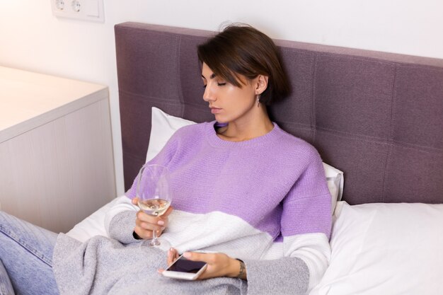 Mujer en casa aburrida cansada se durmió con una copa de vino y un teléfono en la mano