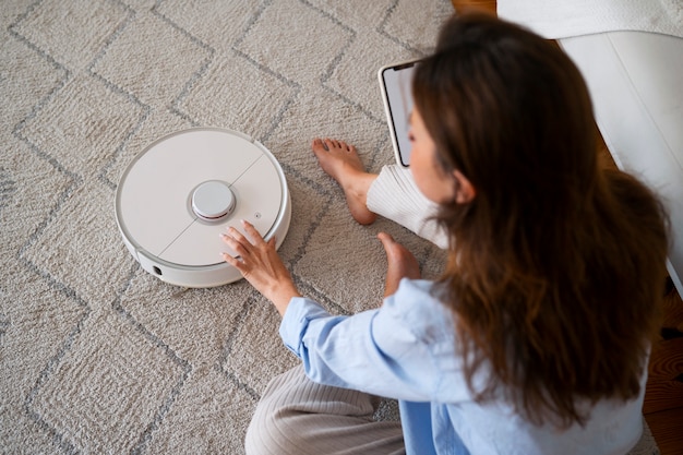 Foto gratuita mujer en casa con aspiradora robótica inalámbrica