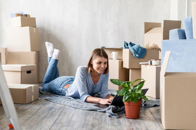 Mujer en casa con cajas y planta para mudarse