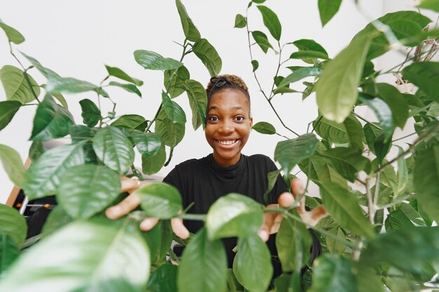 Mujer en casa. Chica con un suéter negro. Mujer africana en la oficina. Persona con maceta.