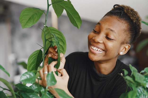 Mujer en casa. Chica con un suéter negro. Mujer africana en la oficina. Persona con maceta.