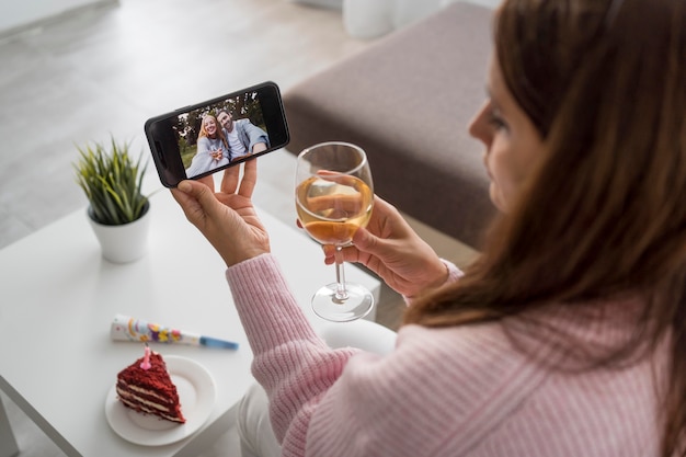 Foto gratuita mujer en casa en cuarentena tomando una copa con un amigo a través de smartphone