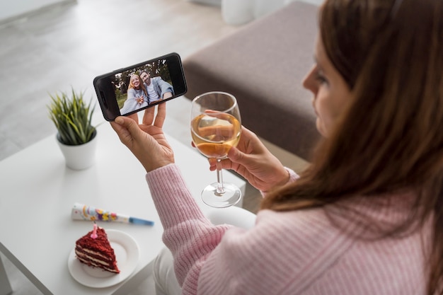 Mujer en casa en cuarentena tomando una copa con un amigo a través de smartphone