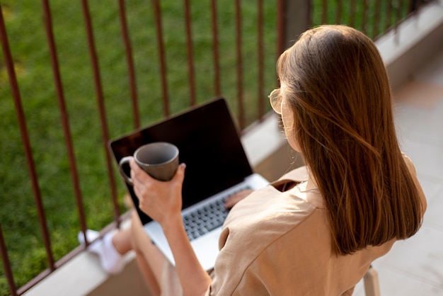 Mujer en casa en cuarentena trabajando con portátil al aire libre