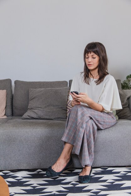 Mujer en casa en sofá con smartphone