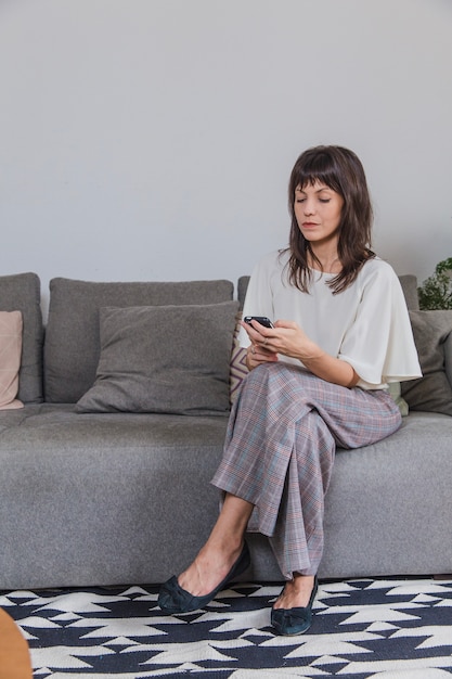 Mujer en casa en sofá con smartphone