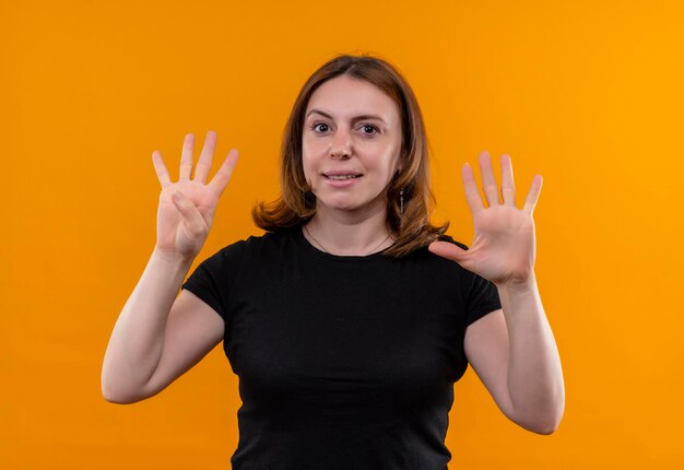 Mujer casual joven complacida que muestra cuatro y cinco en el espacio naranja aislado