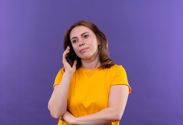 Mujer casual joven confiada que habla por teléfono en el espacio púrpura aislado con el espacio de la copia