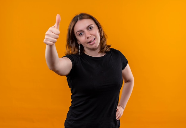 Foto gratuita mujer casual joven confiada que muestra el pulgar hacia arriba con la mano en la cintura en el espacio naranja aislado con espacio de copia